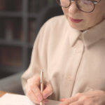 Die technische Dokumentation gilt als Herzstück für die Zulassung von Medizinprodukten. Eine ältere Frau macht sich Notizen mit einem Kugelschreiber.